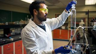 一个学生在化学实验室里把烧杯里的液体倒进试管里.